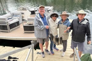 A group of 2 men and 2 women show off their catch of 11 trout as they get off of their pontoon rental on Lake San Cristobal.
