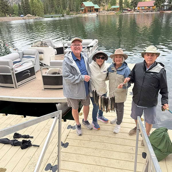 A group of 2 men and 2 women show off their catch of 11 trout as they get off of their pontoon rental on Lake San Cristobal.