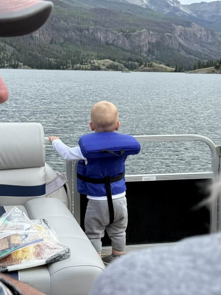 A little angler in a blue life vest looks out at Lake San Cristobal from the deck of the DFS pontoon.